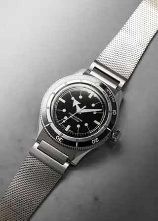 An angled view of the black dial, bezel and mesh bracelet.