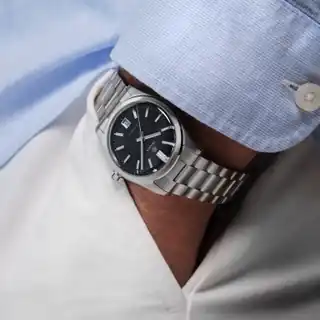 The date version on a wrist in TRASKA’s photograph. The wearer’s wrist measurement is not supplied.